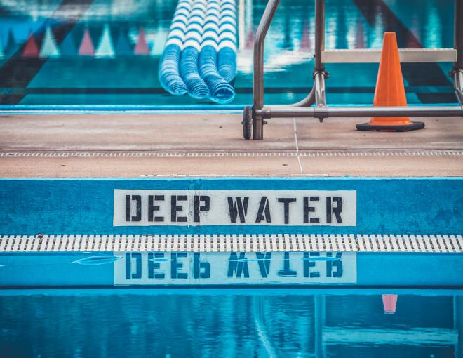 the edge of a swimming pool with a sign that says 'deep water'